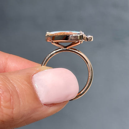 An Australian Opal Ring by NIXIN Jewelry held to show its profile. A rose gold opal ring.