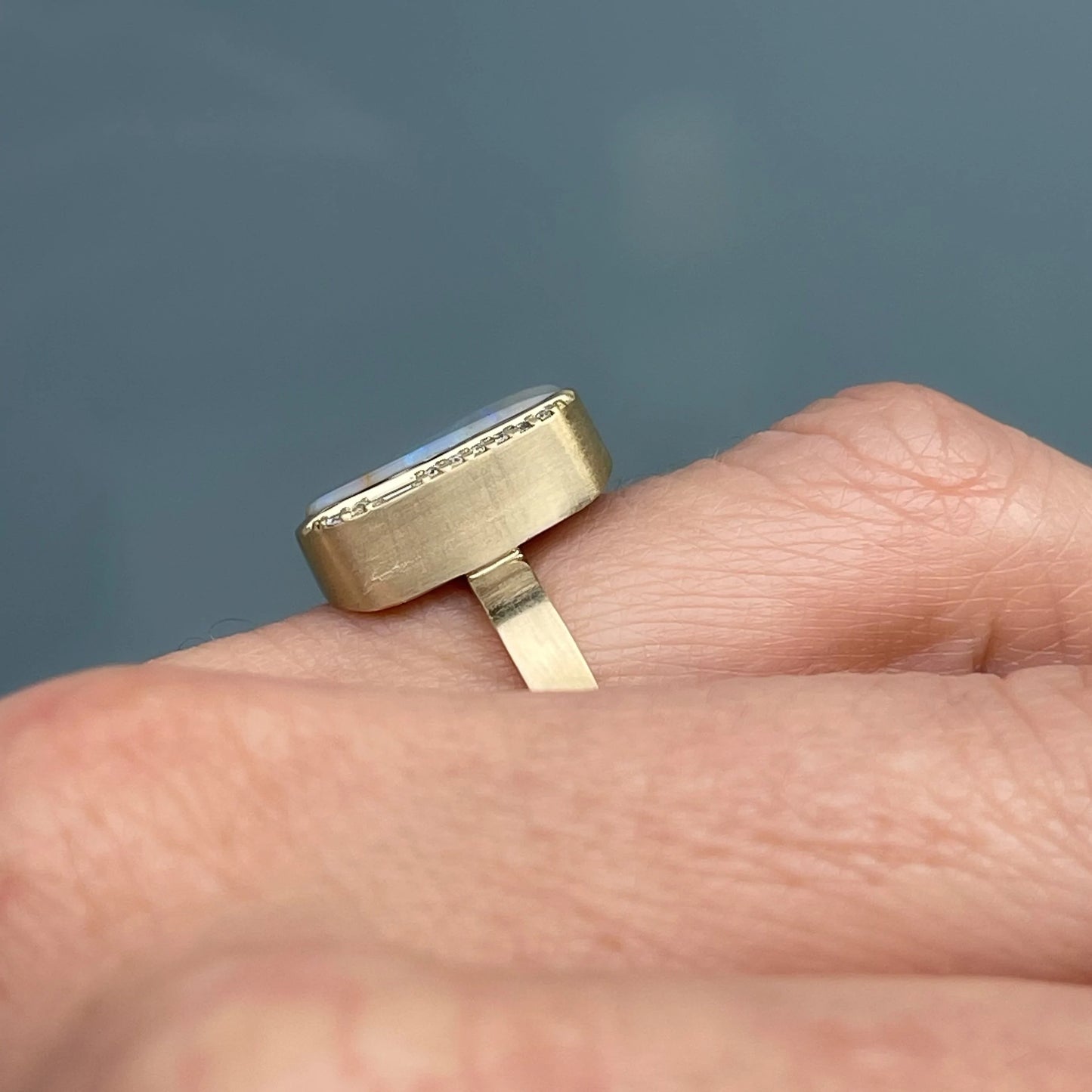 An Australian Opal Ring by NIXIN Jewelry is modeled on a hand and shown in profile to display the height of its gold setting.