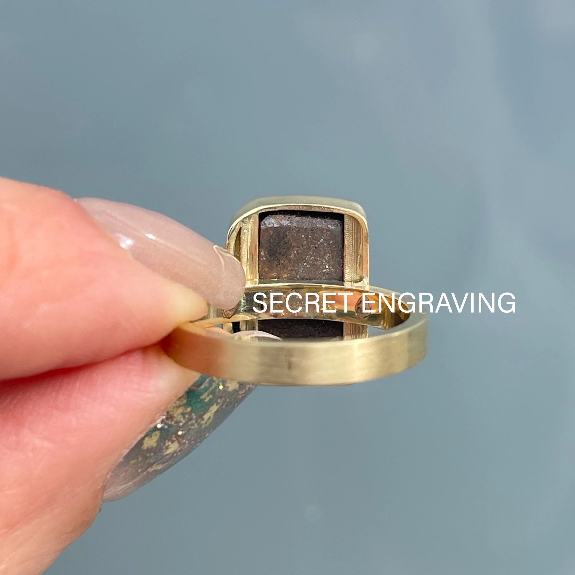 An Australian Opal Ring by NIXIN Jewelry with a Boulder Opal set in 14k gold, shown from behind to indicate the spot of the secret engraving.