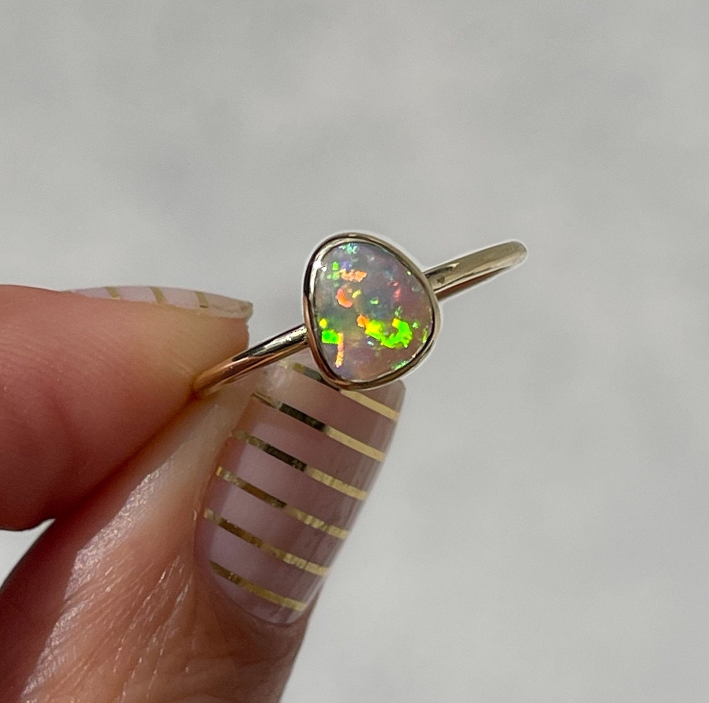 Hand holding green opal ring in gold by NIXIN Jewelry
