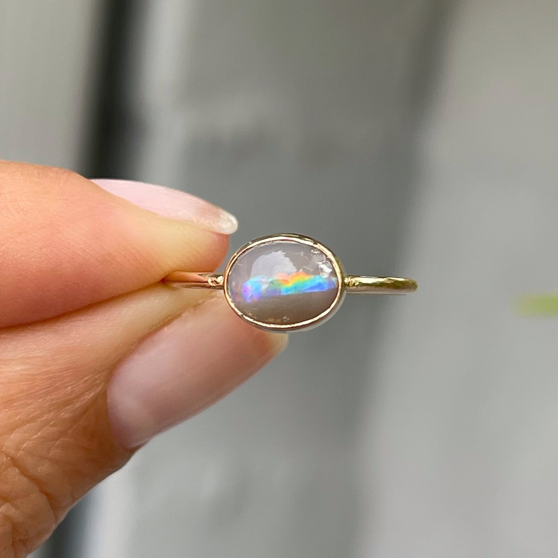Hand holding rainbow opal ring by NIXIN Jewelry