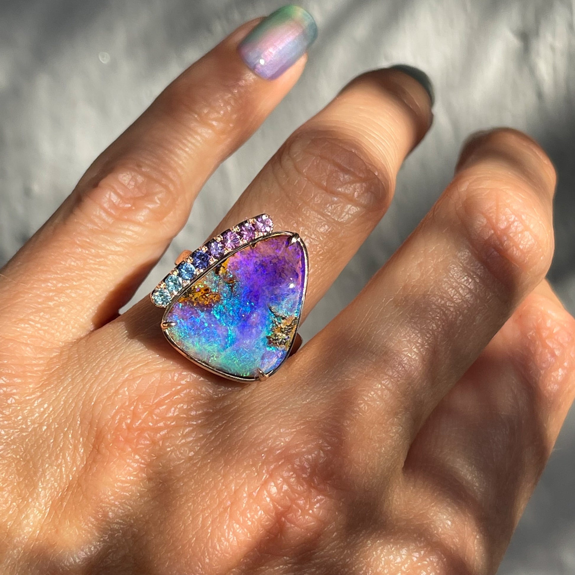 An Australian Opal Ring by NIXIN Jewelry featuring a large pipe opal is shown on a model's hand.