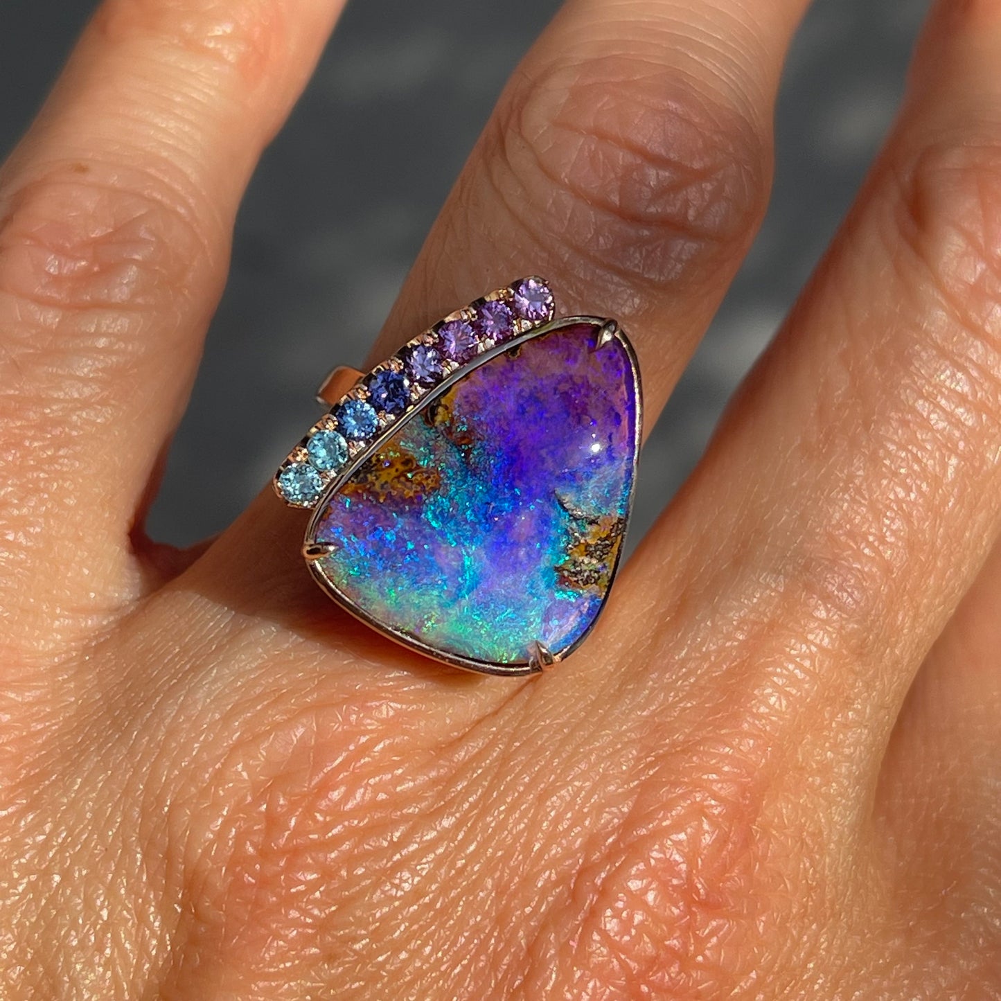 Close up of an Australian Opal Ring by NIXIN Jewelry made with matching blue and purple sapphires.