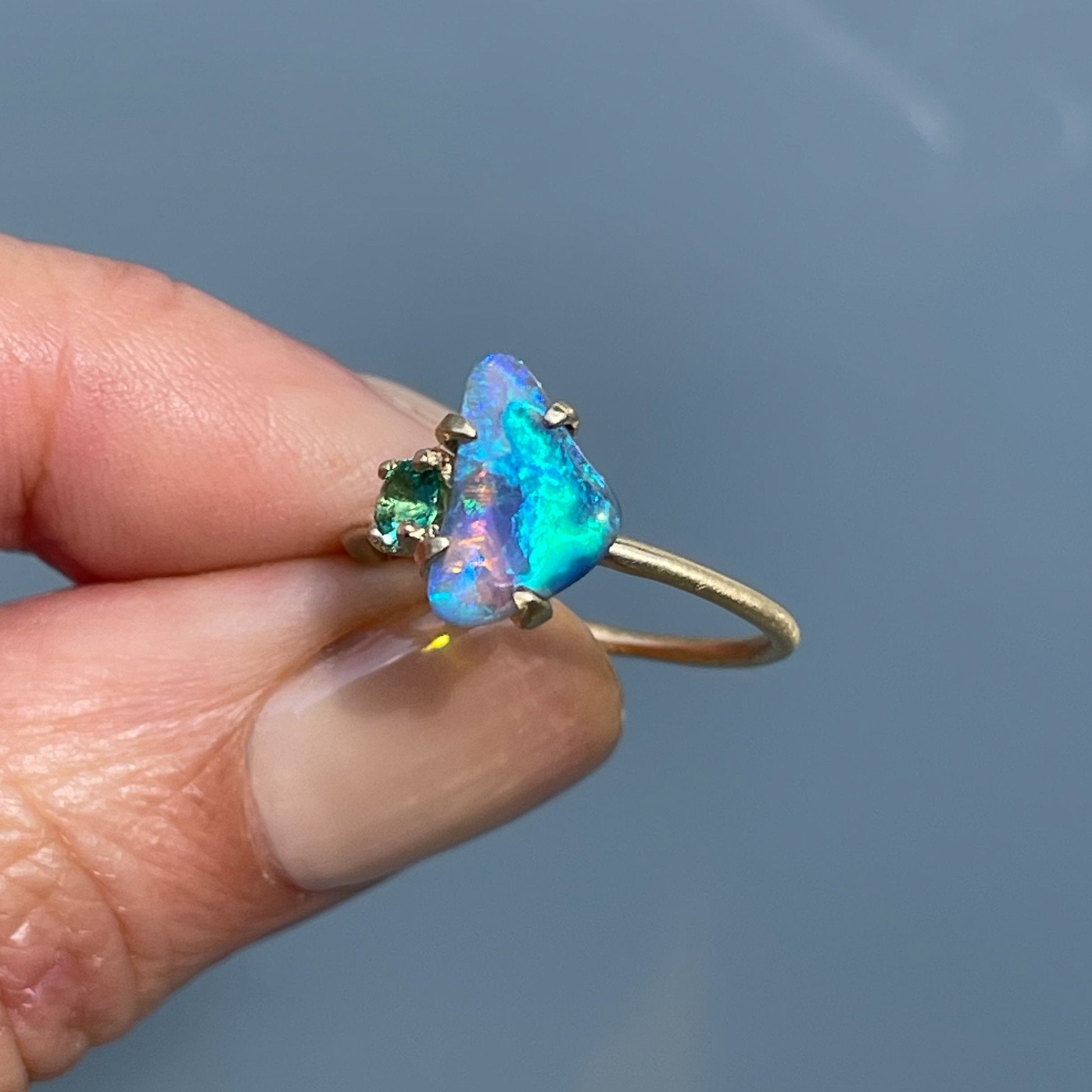 Black opal ring by NIXIN Jewelry held in sunlight