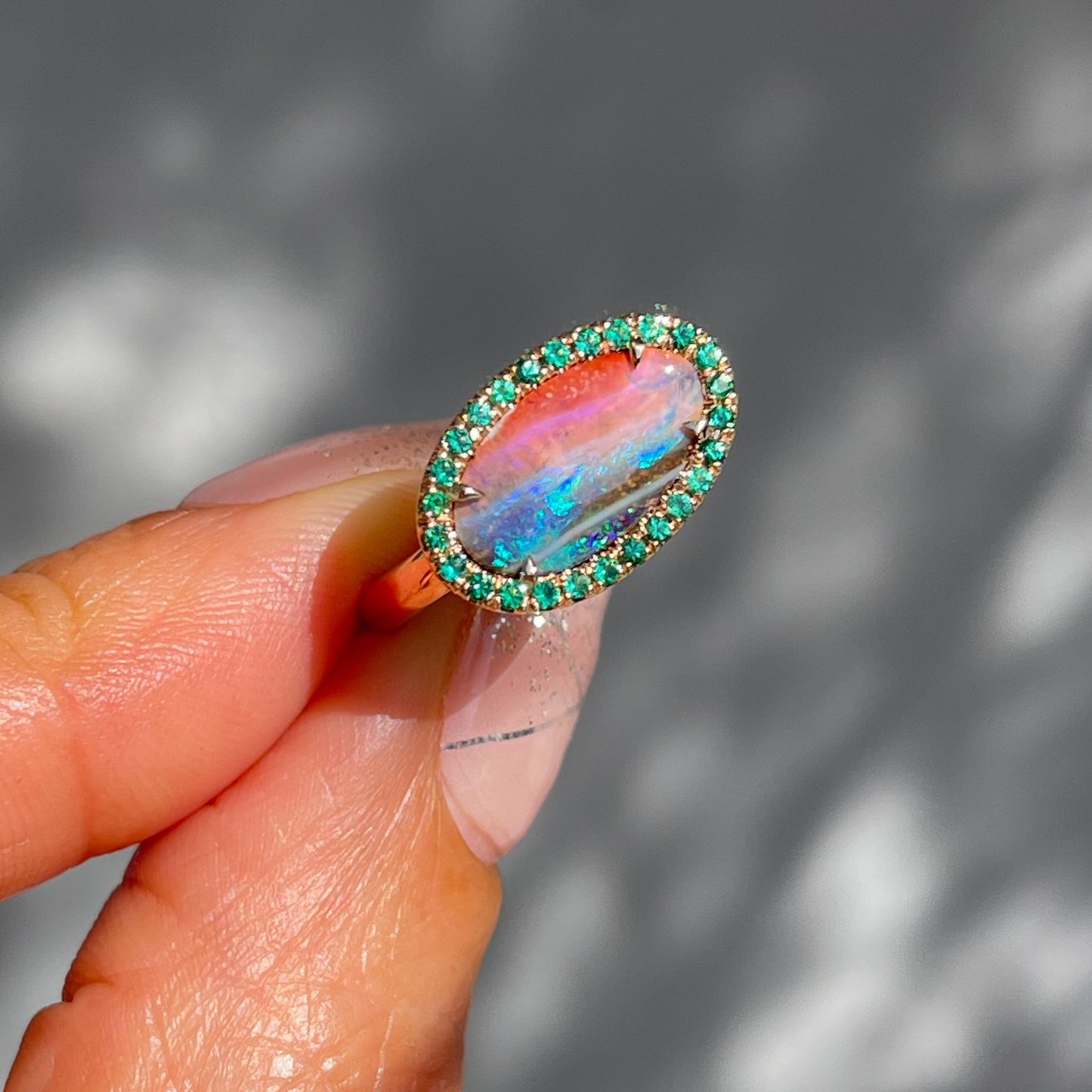 Australian Opal and Emerald Ring by NIXIN Jewelry held in sun. Boulder opal ring.