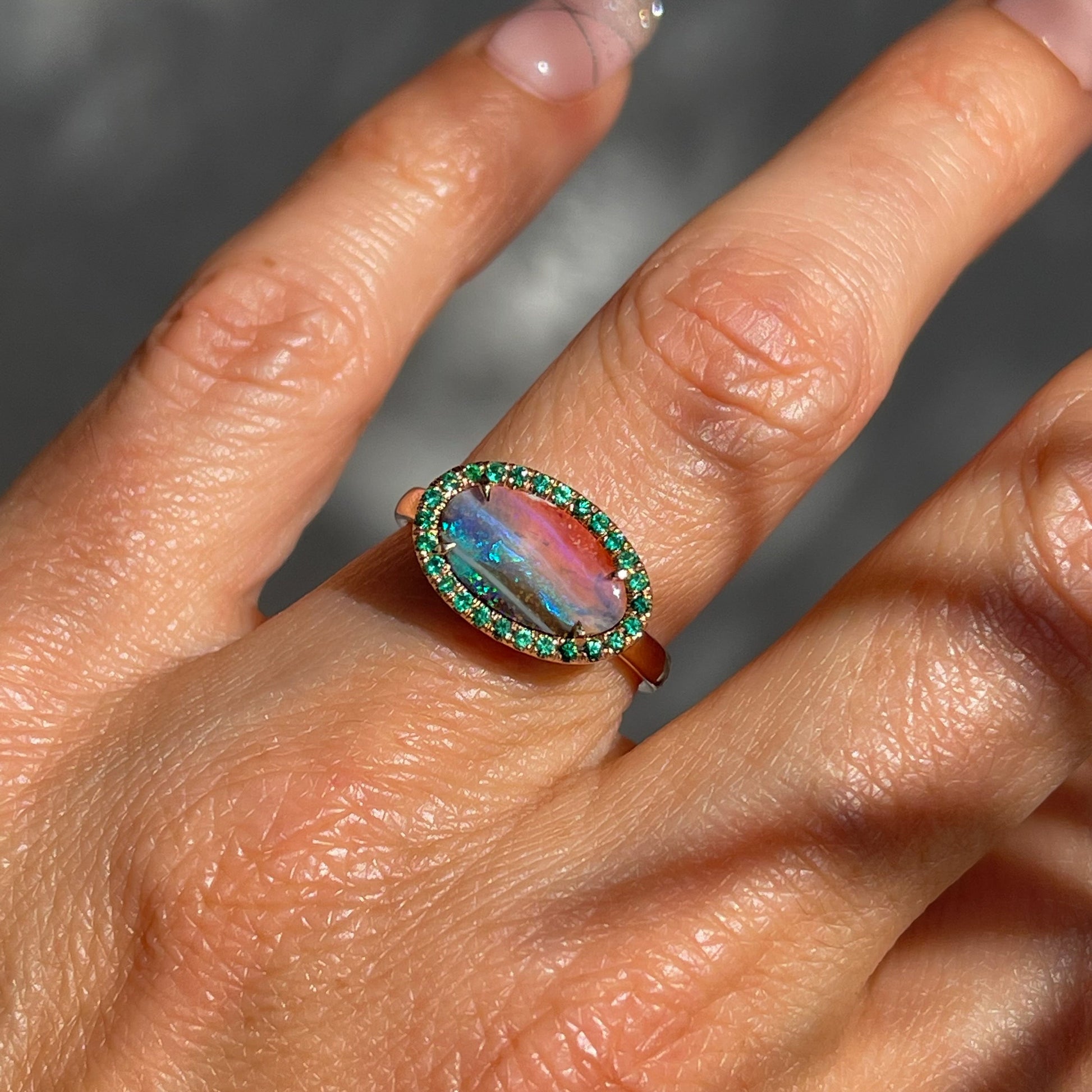 Australian Opal and Emerald Ring by NIXIN Jewelry modeled on hand. Blue and pink opal in 14k rose gold.