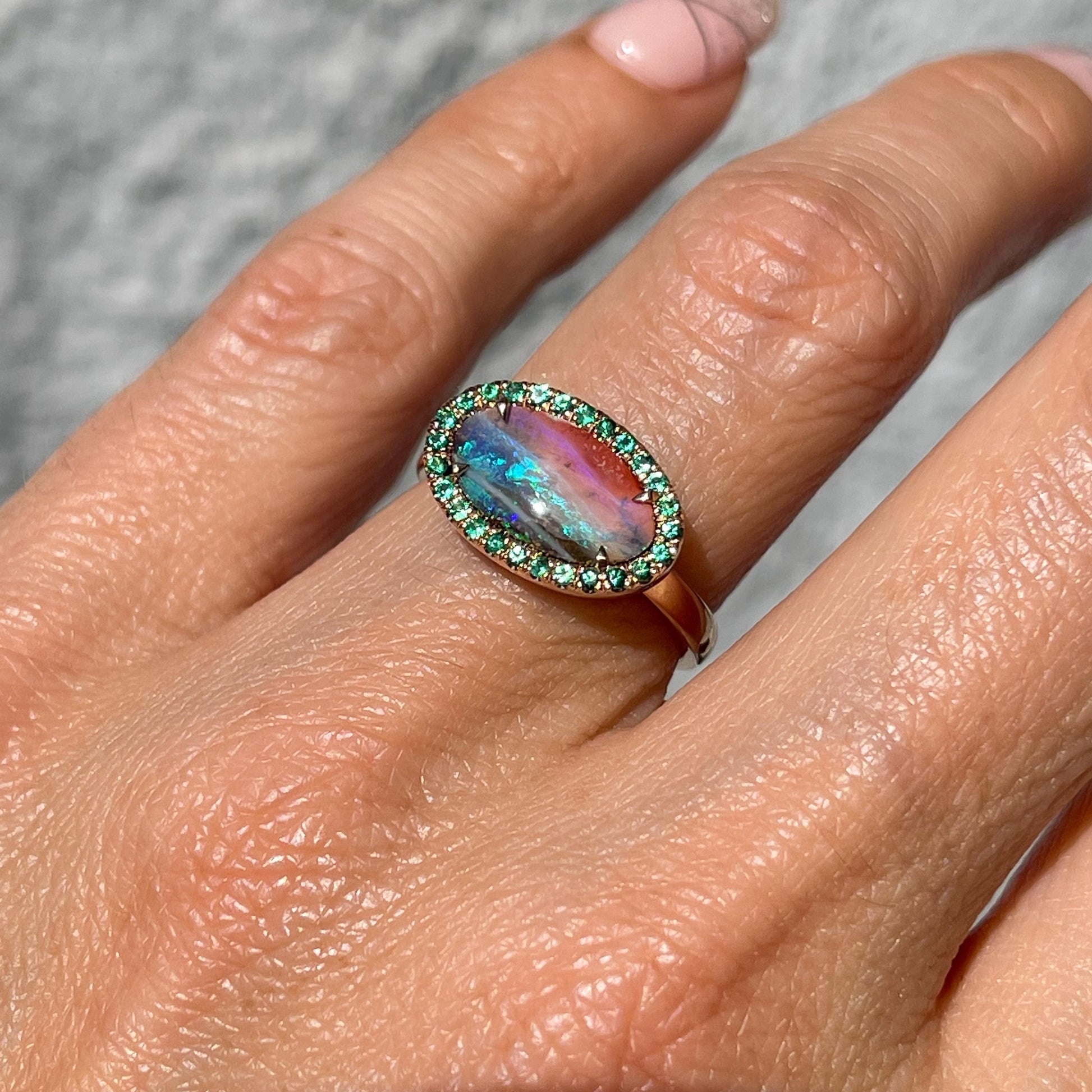 Australian Opal and Emerald Ring by NIXIN Jewelry by NIXIN Jewelry modeled on hand in direct sunlight. Oval opal ring.