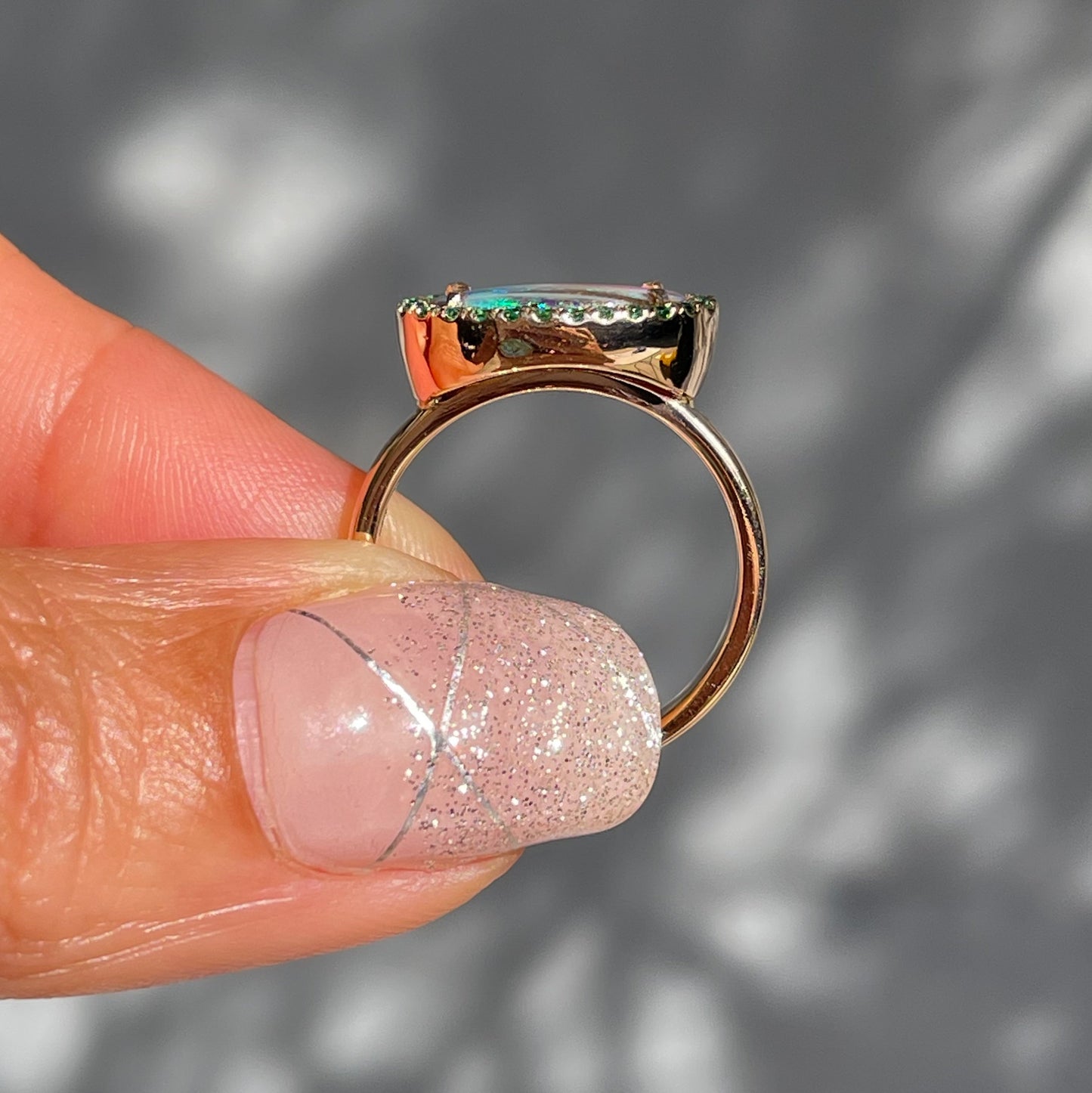 Australian Opal and Emerald Ring by NIXIN Jewelry held showing profile. Rose gold emerald opal ring.