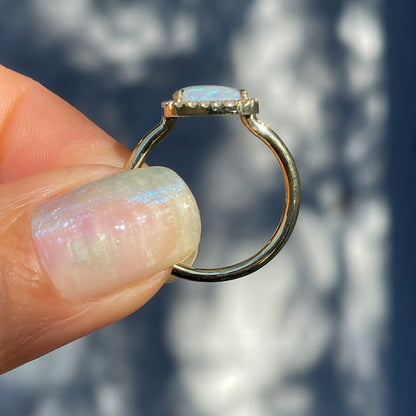 An Australian Opal Ring by NIXIN Jewelry held in profile. A gold opal ring.