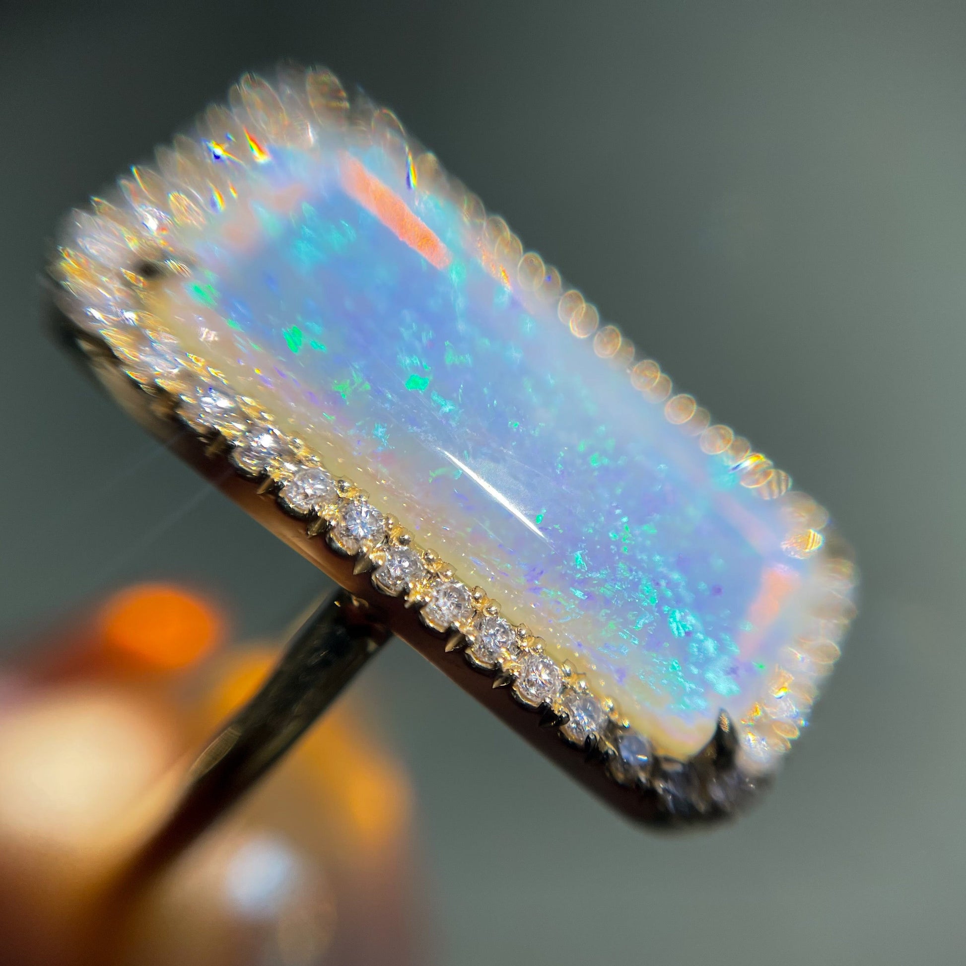 Magnified shot of an Australian Opal Ring by NIXIN Jewelry. Shows a crystal opal ring with diamonds set in yellow gold.