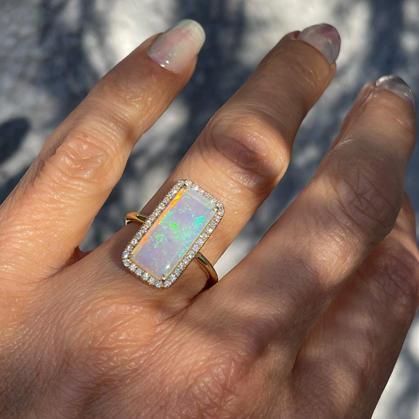 An Australian Opal Ring by NIXIN Jewelry modeled on the hand. The Crystal Opal shows a lavender base with blue and green fire.