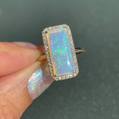 An Australian Opal Ring by NIXIN Jewelry held in front of a frosted glass background. A natural opal ring.