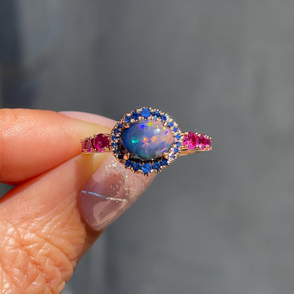 Sapphire and Opal Ring by NIXIN Jewelry held in sun. Rose gold Australian opal ring.