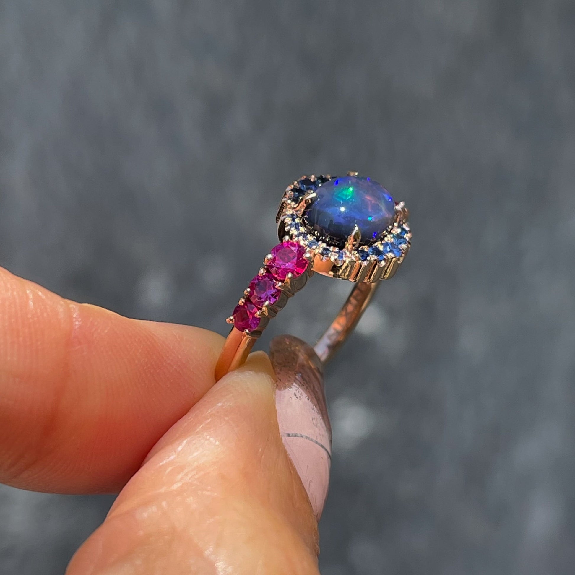 Sapphire and Opal Ring by NIXIN Jewelry held showing side. Black opal and sapphire ring.