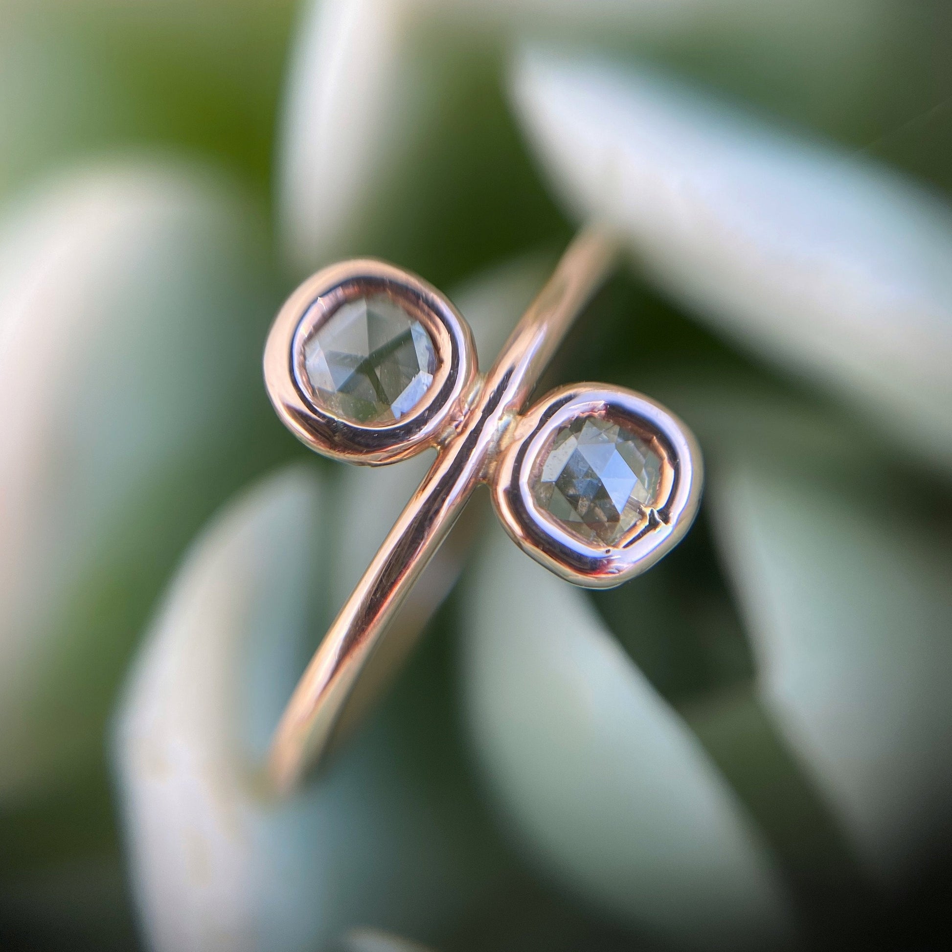 Paleo Double Diamond Slice Rose Gold Ring close up against a succulent