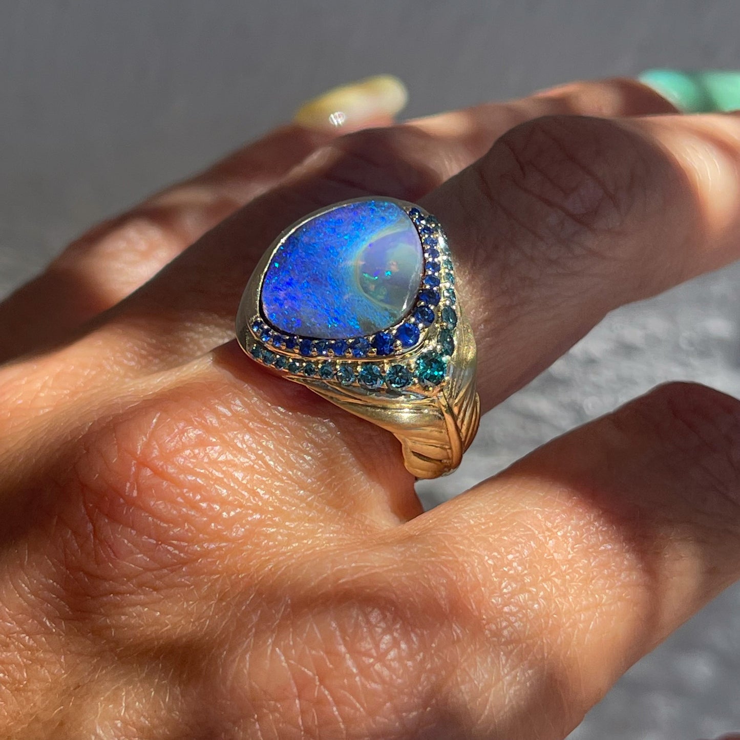 Australian Opal Ring by NIXIN Jewelry modeled on hand. Gold feather ring with Australian opal and sapphires and diamonds.