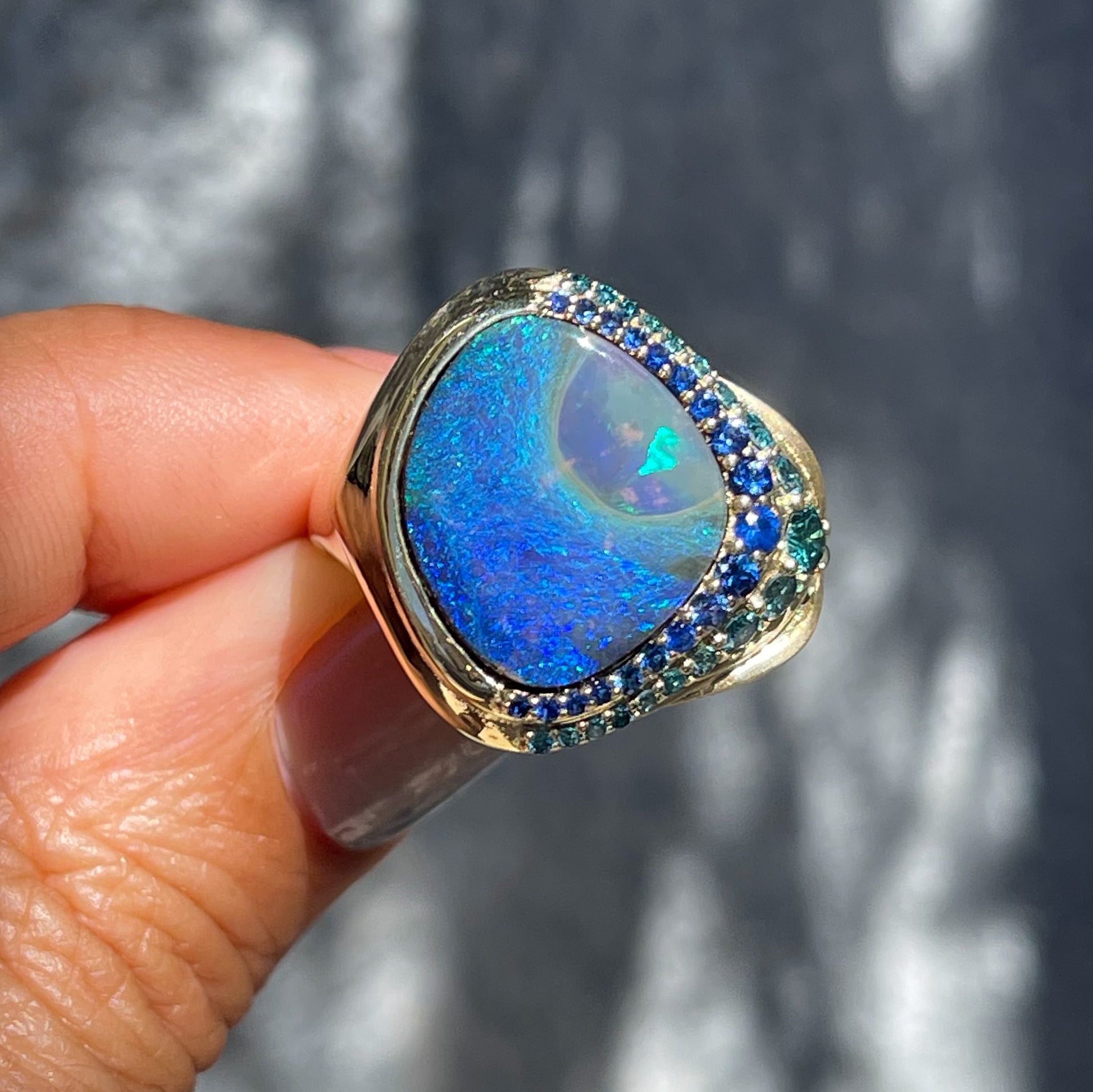 Australian Opal Ring by NIXIN Jewelry held in sun. Gold opal ring with sapphires and diamonds.
