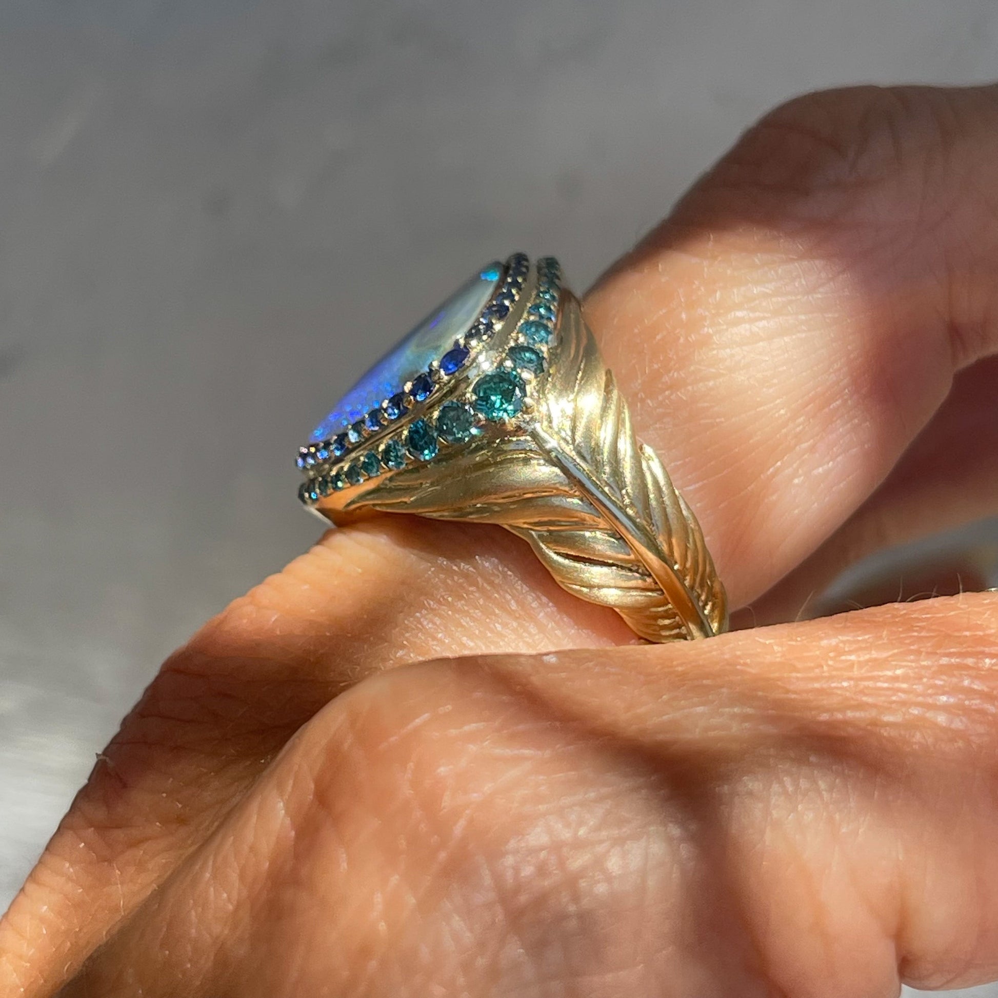 Australian Opal Ring by NIXIN Jewelry on finger showing side of feather band. Blue sapphire and diamond feather ring.