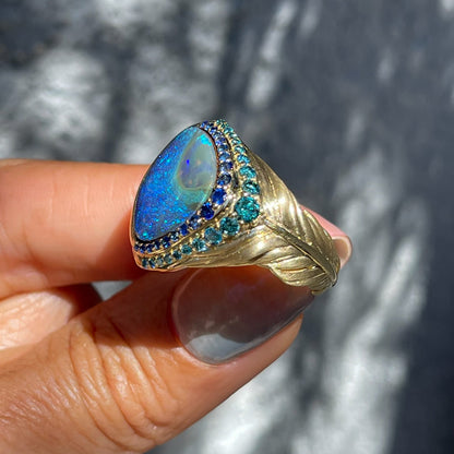 Australian Opal Ring by NIXIN Jewelry held showing side of gold band with feather detail. Blue opal ring.