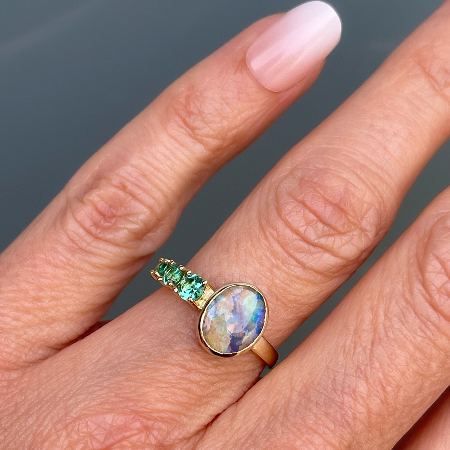 Black opal ring with emeralds by NIXIN Jewelry shown on hand