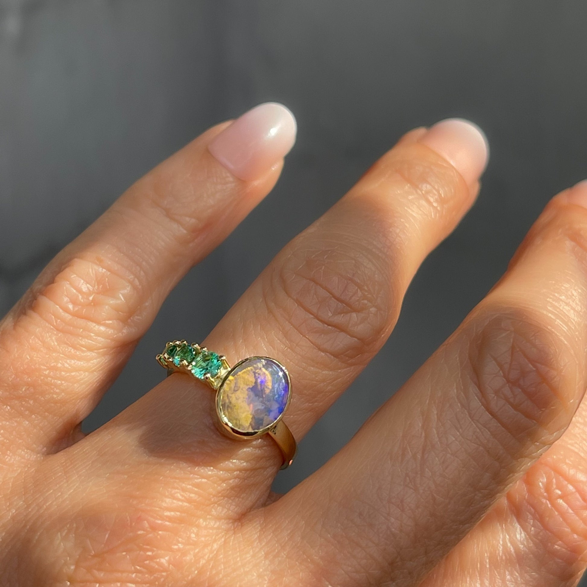 Oval opal ring with emeralds by NIXIN Jewelry worn in sunlight