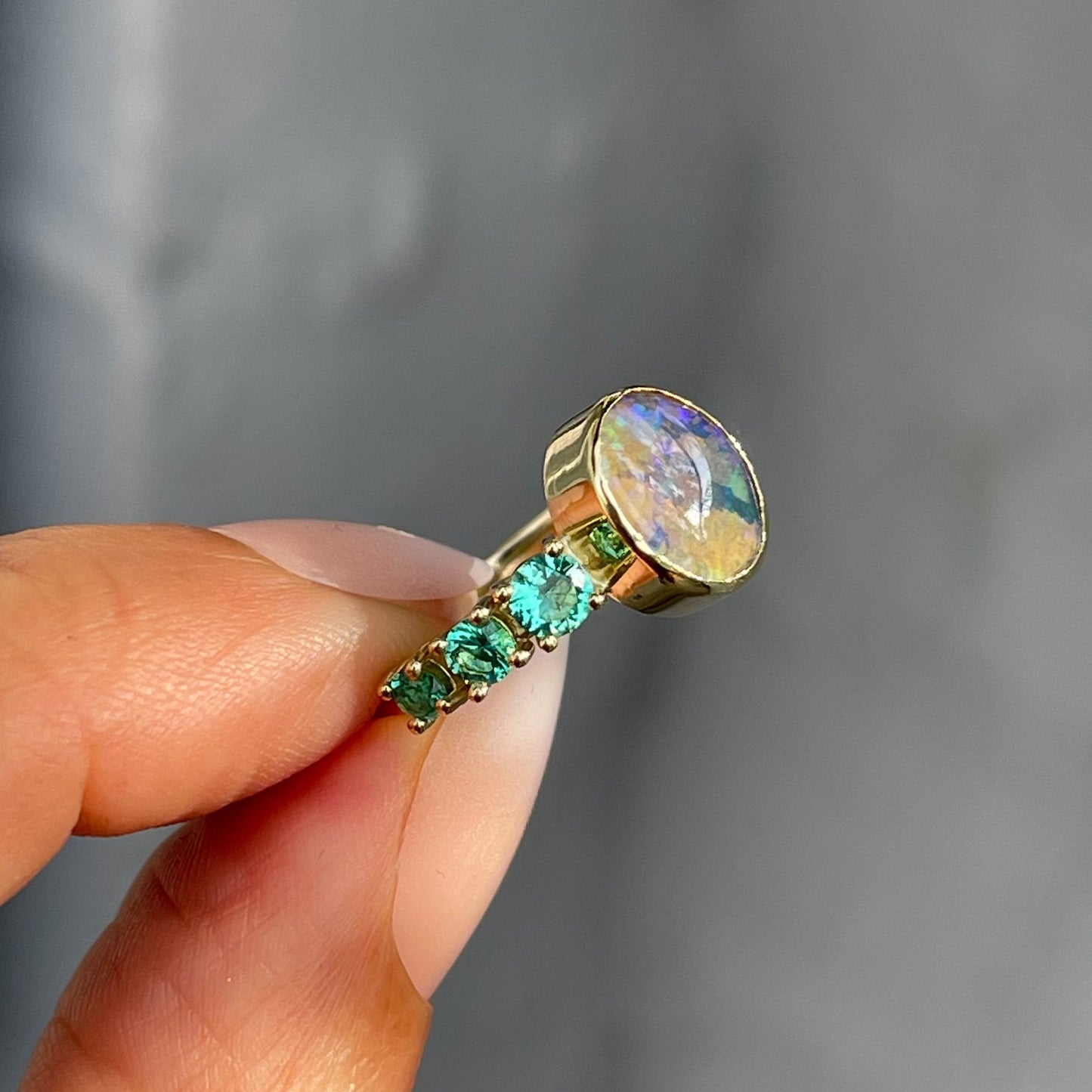 Emerald and Australian opal ring in 14k gold by NIXIN Jewelry held in profile