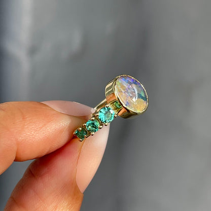 Emerald and Australian opal ring in 14k gold by NIXIN Jewelry held in profile