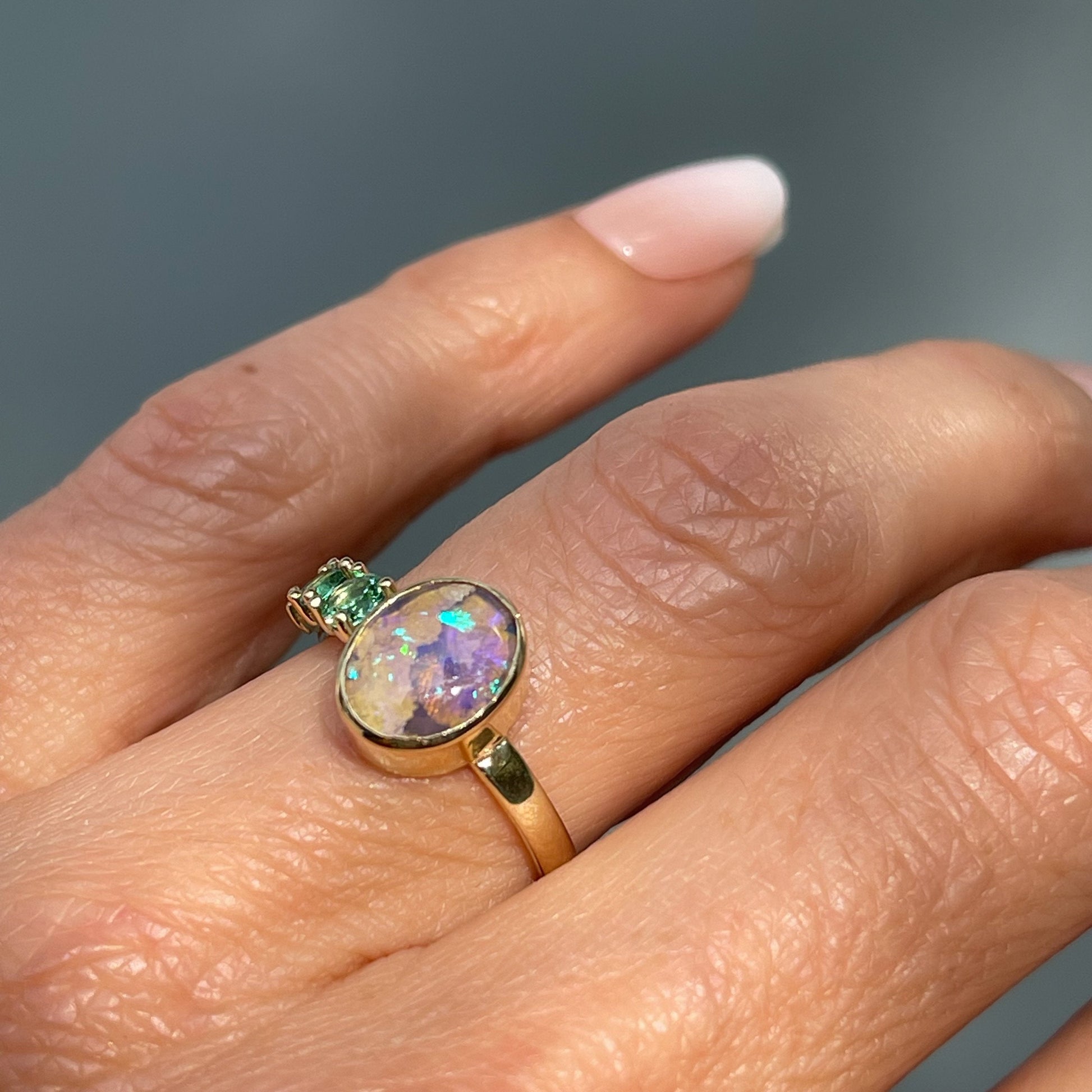 Gold opal ring with Australian Opal and emeralds by NIXIN Jewelry shown on hand