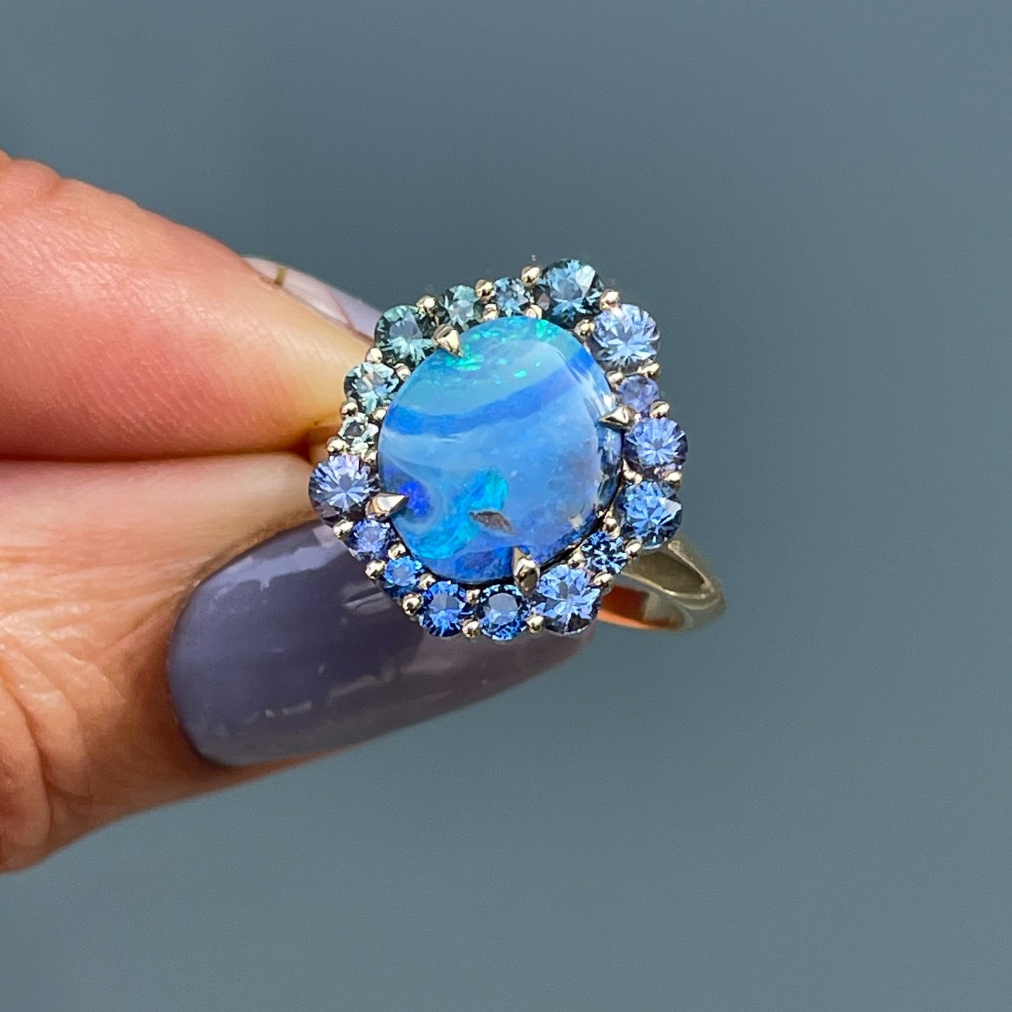 Australian Opal Ring by NIXIN Jewelry held in the sun. Boulder opal ring set in 14k yellow gold.