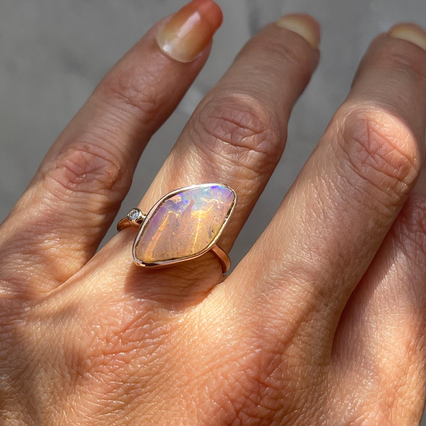 Zion Dali Australian Opal Ring by NIXIN Jewelry modeled on hand. Rose gold opal ring.