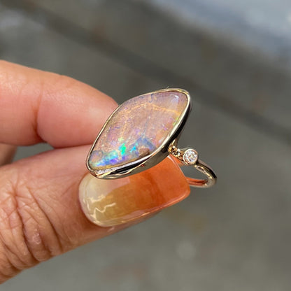 Zion Dali Australian Opal Ring by NIXIN Jewelry held in sunlight. Diamond and opal rings.